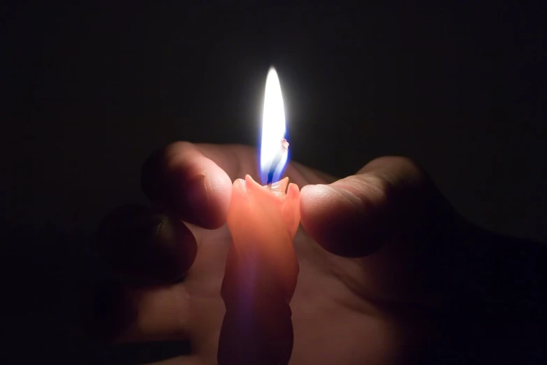 a person is holding a lit candle in their hand
