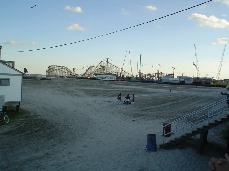 people standing in the sand next to roller coasters