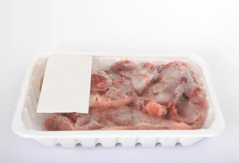 a plastic container holds some meat, and a blank note