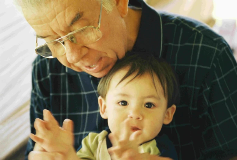 an older man with glasses on, next to his little boy