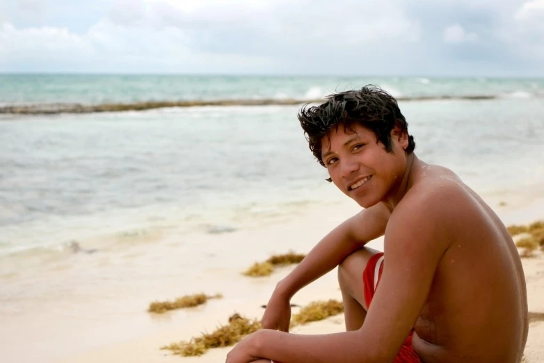 a man that is sitting down on some sand