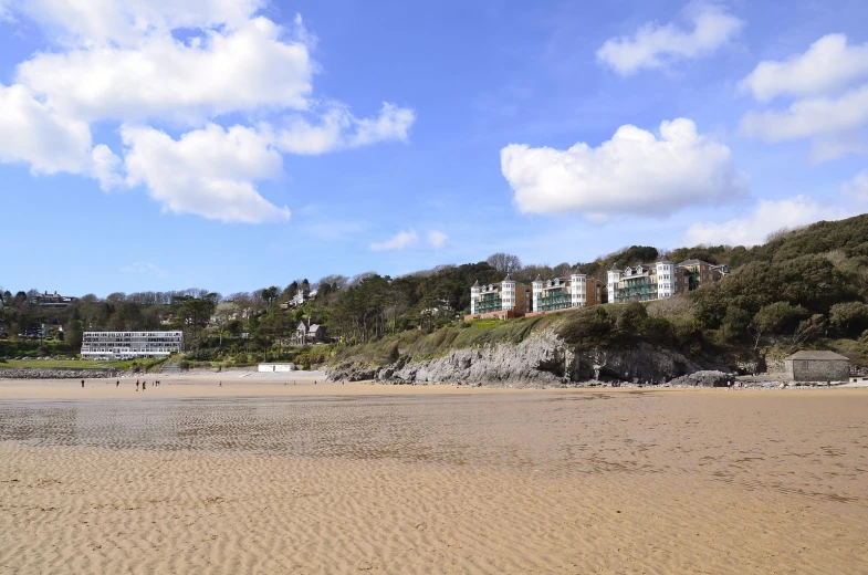 a beach area with the ocean and houses on the hill