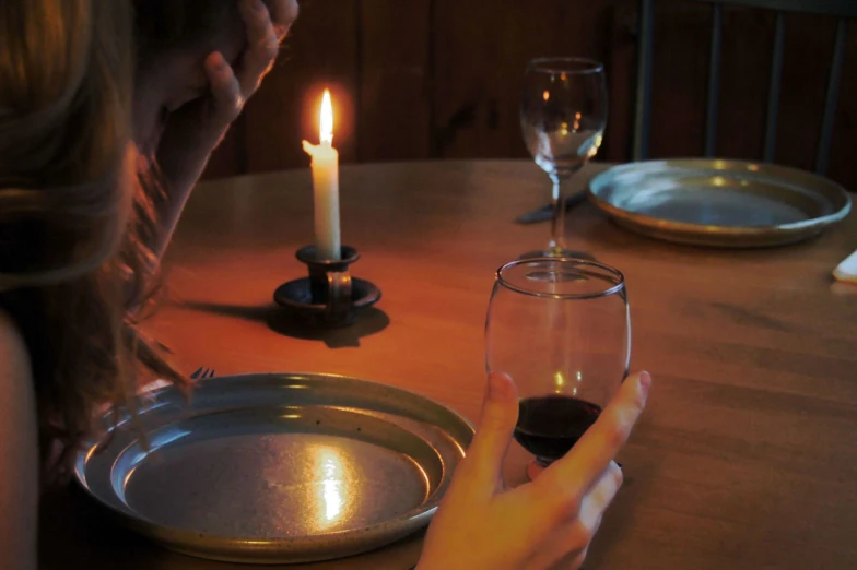 two hands holding glass with black substance sitting on wooden table