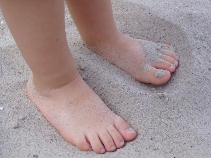 a childs feet are covered in sand on the beach