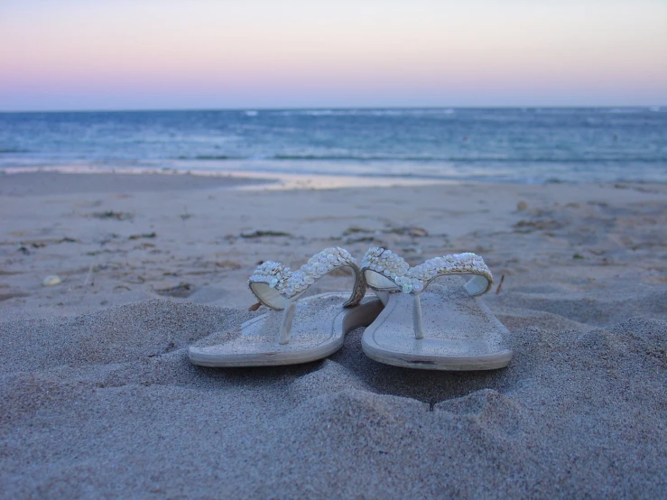a pair of sandals on the beach with the ocean in the background