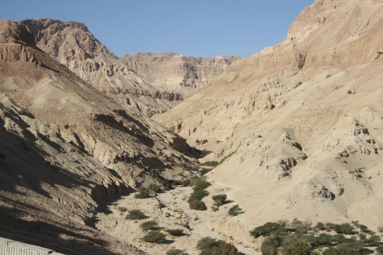 a valley surrounded by cliffs and trees with mountains in the distance