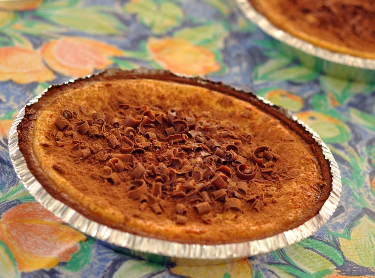 a baked dessert sitting on top of a floral tablecloth