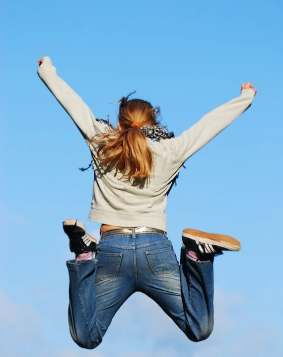 a woman leaping in the air with her arms outstretched