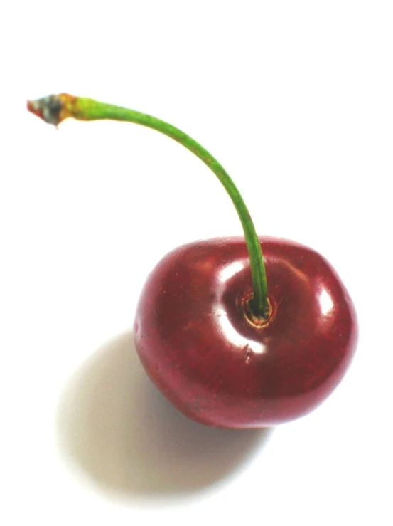 a single single cherry sits on a white table