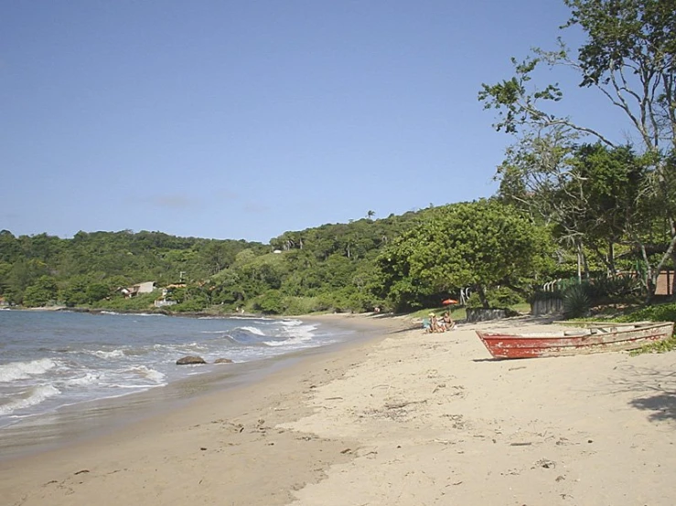 a red boat sitting on top of a sandy beach