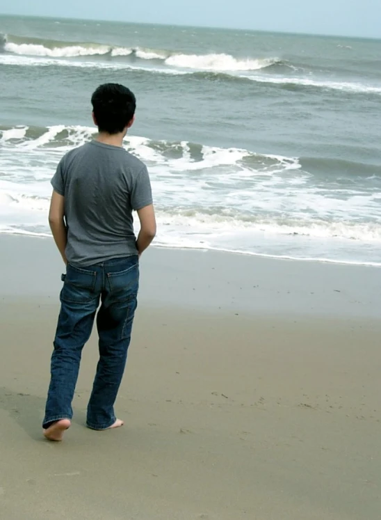 a man standing on the shore watching waves come in