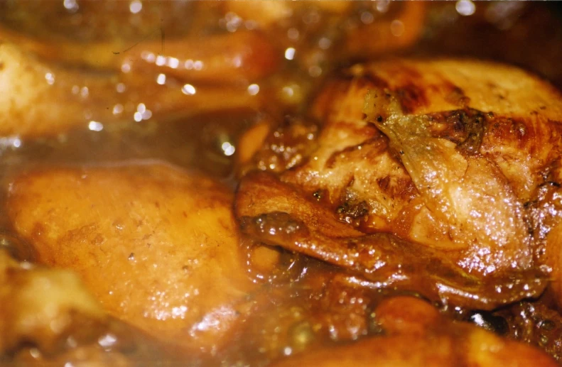 meat cooking in a pot with sauce on top of it