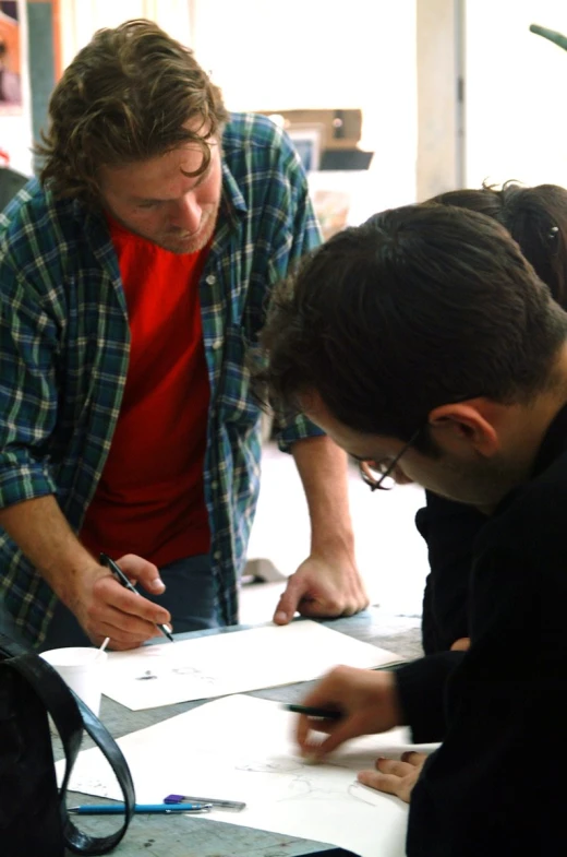 two men looking at an electronic screen and some papers