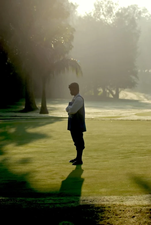 a man standing in the sunlight on the putting green