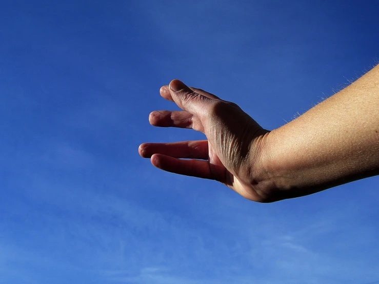 someone's hand with one small object hovering in the sky