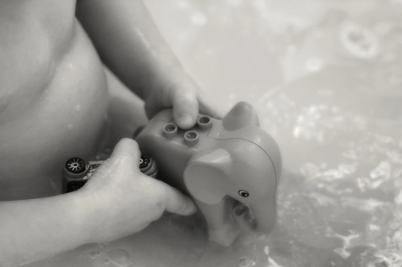 a mother playing with her baby's toy in a bathtub