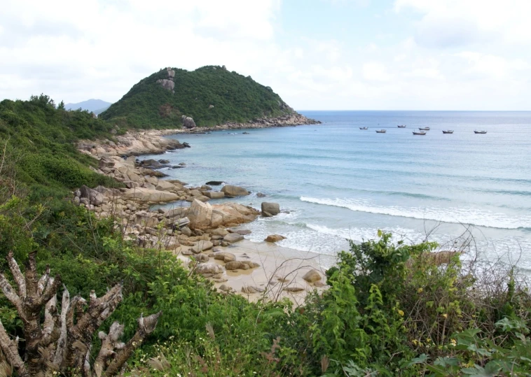 a beach is surrounded by rocky outcrops and sea grass