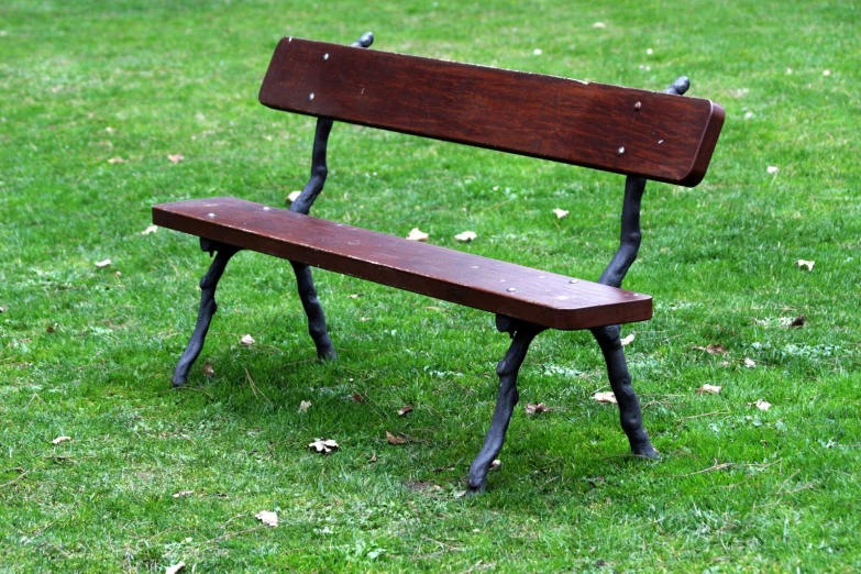 a wooden bench in the middle of a grassy field