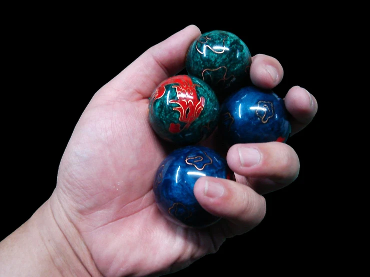 a person holding three colorful ball ornaments in their hand