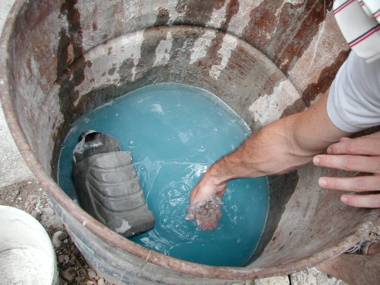 a person reaching in to the blue water