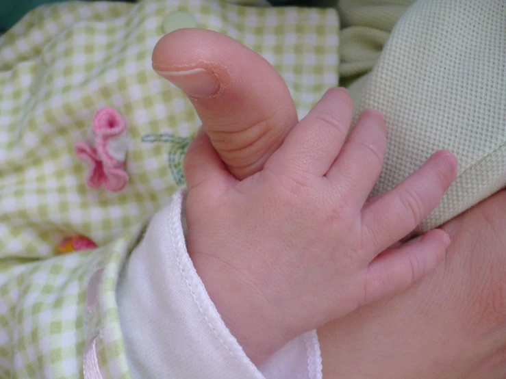 a baby girl with a pink ribbon is holding her hand