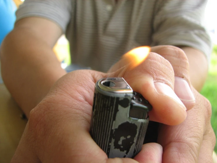 someone is lighting a small lighter in the hand