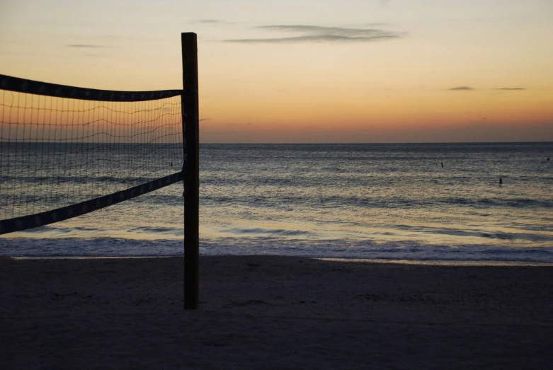 the volleyball net sits on the beach in front of the ocean