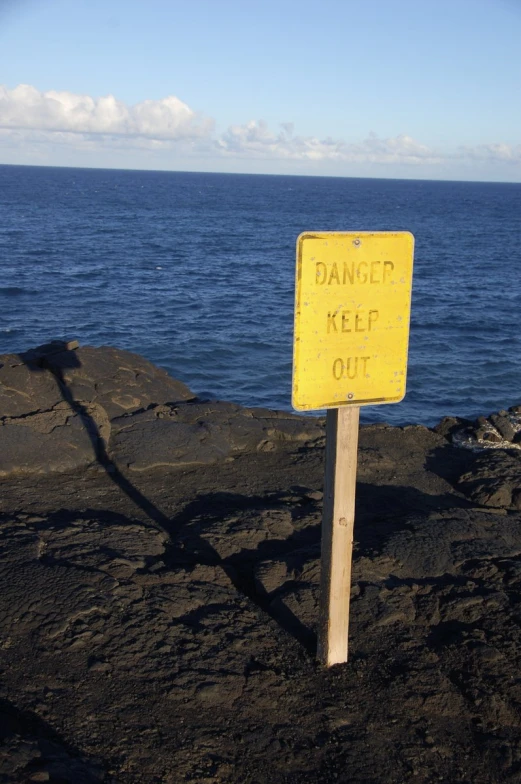 a sign is on the rocks by the water