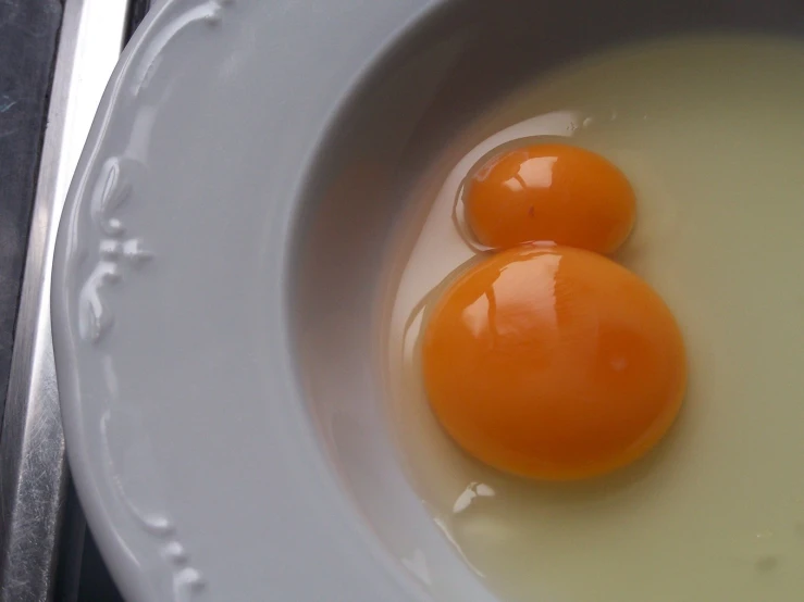 two eggs in a bowl next to a spoon