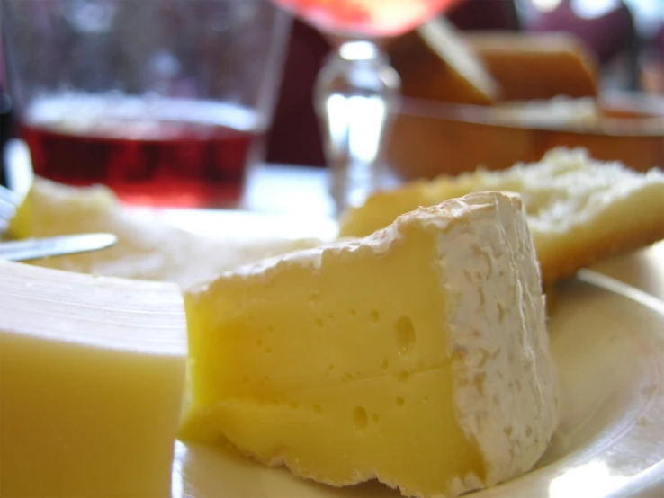 cheese on the plate with wine and glass behind it