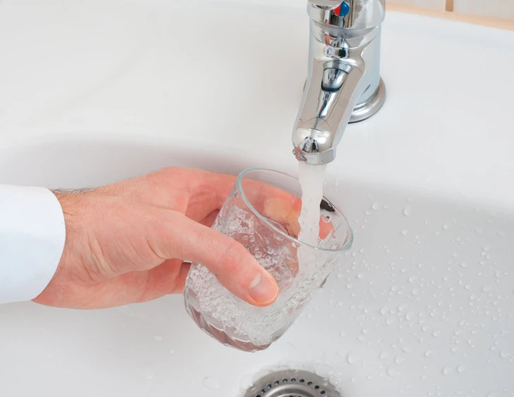 someone is holding their drink to the faucet running