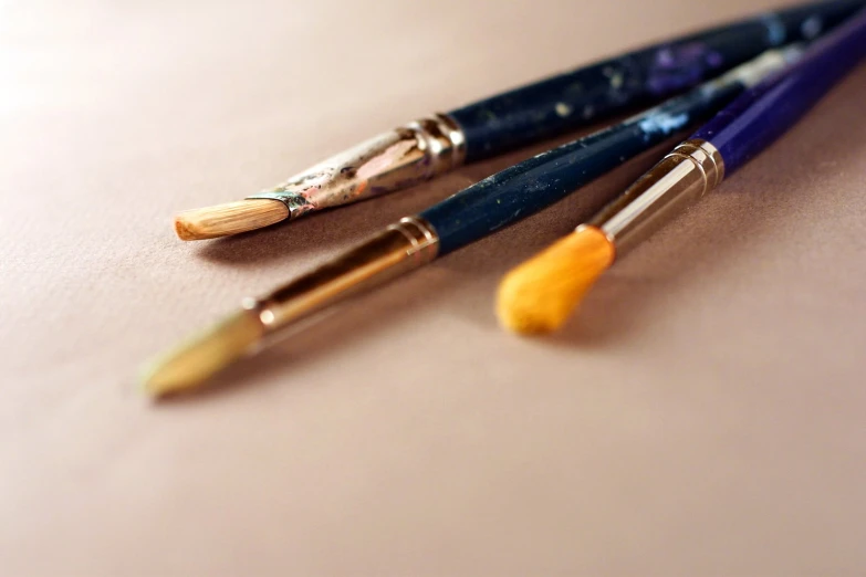 three artistic brushes, one yellow and one blue