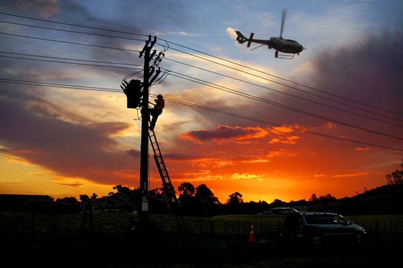 a helicopter is flying over an electricity pole