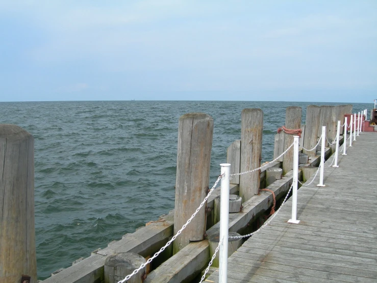 an old dock is near the water, with the sky as a backdrop