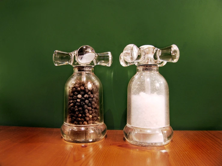 two decorative salt shakers on a table with two pepper mills