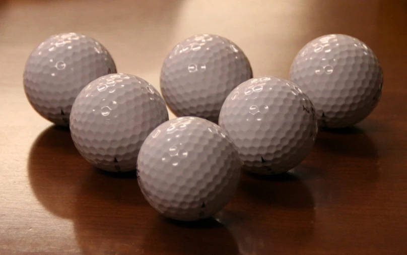 four golf balls on the wooden table, three are not in their own order