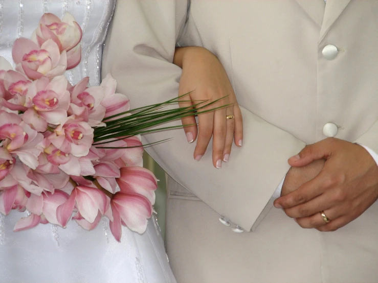 the newly married couple hold bouquets of pink flowers