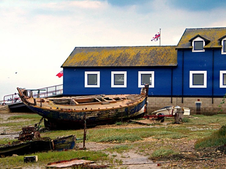 a boat is sitting next to a building in the grass