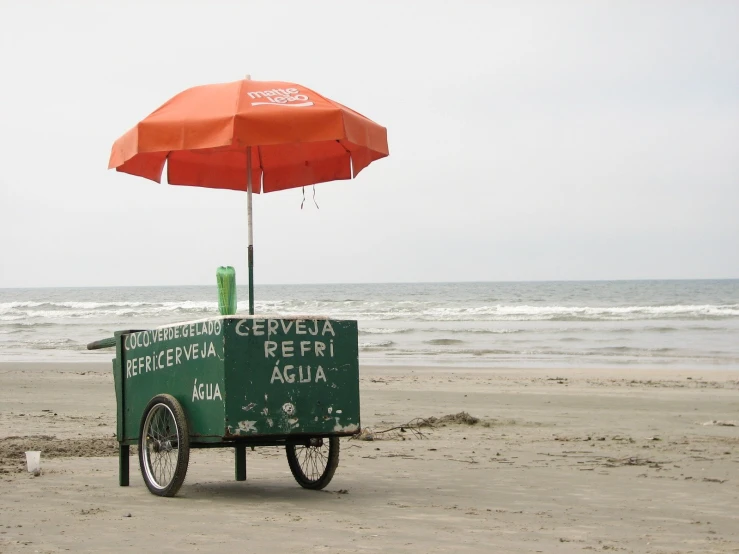 an umbrella is over the small cart on the beach