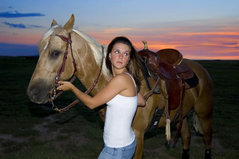 a beautiful young woman standing next to a brown horse