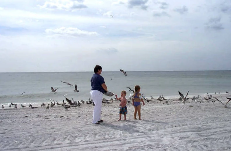 two people are playing with a child at the beach