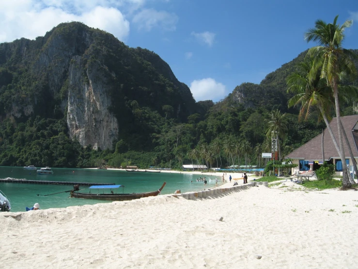 several people are on the beach near boats