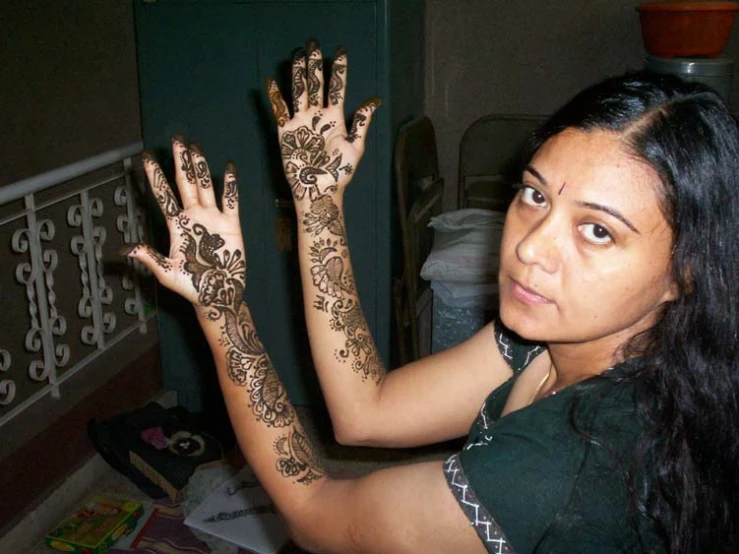 a woman sitting and showing off her henna