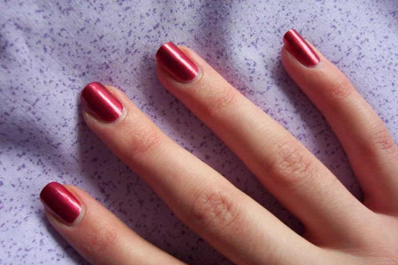 closeup of a red nail on top of someones hand