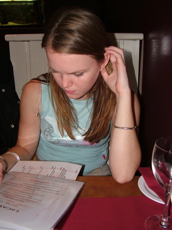 a young woman sitting at a table in front of an open book