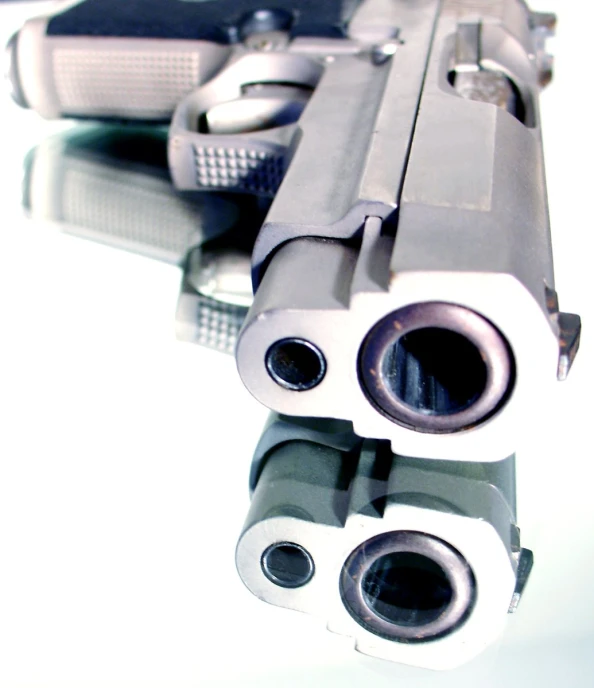 two small guns facing each other on a white table