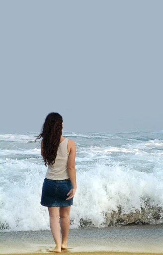a woman is standing by the water looking out to sea