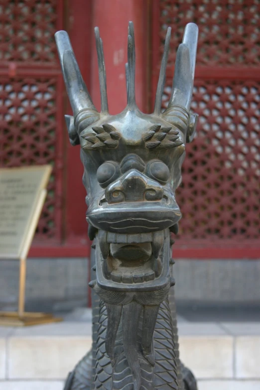 an elaborately designed stone dragon statue in front of a red building