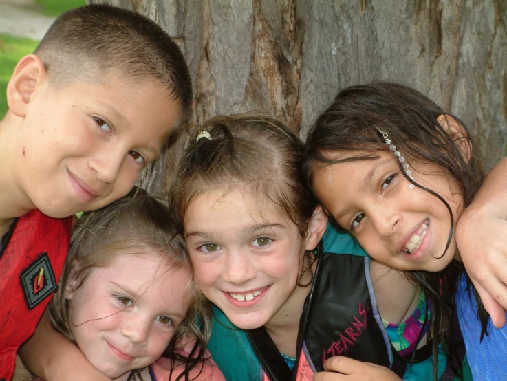 the four children are posing by the tree