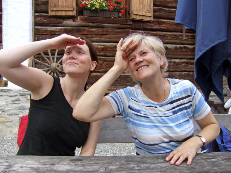 two women sitting outside together and the lady looking at her reflection